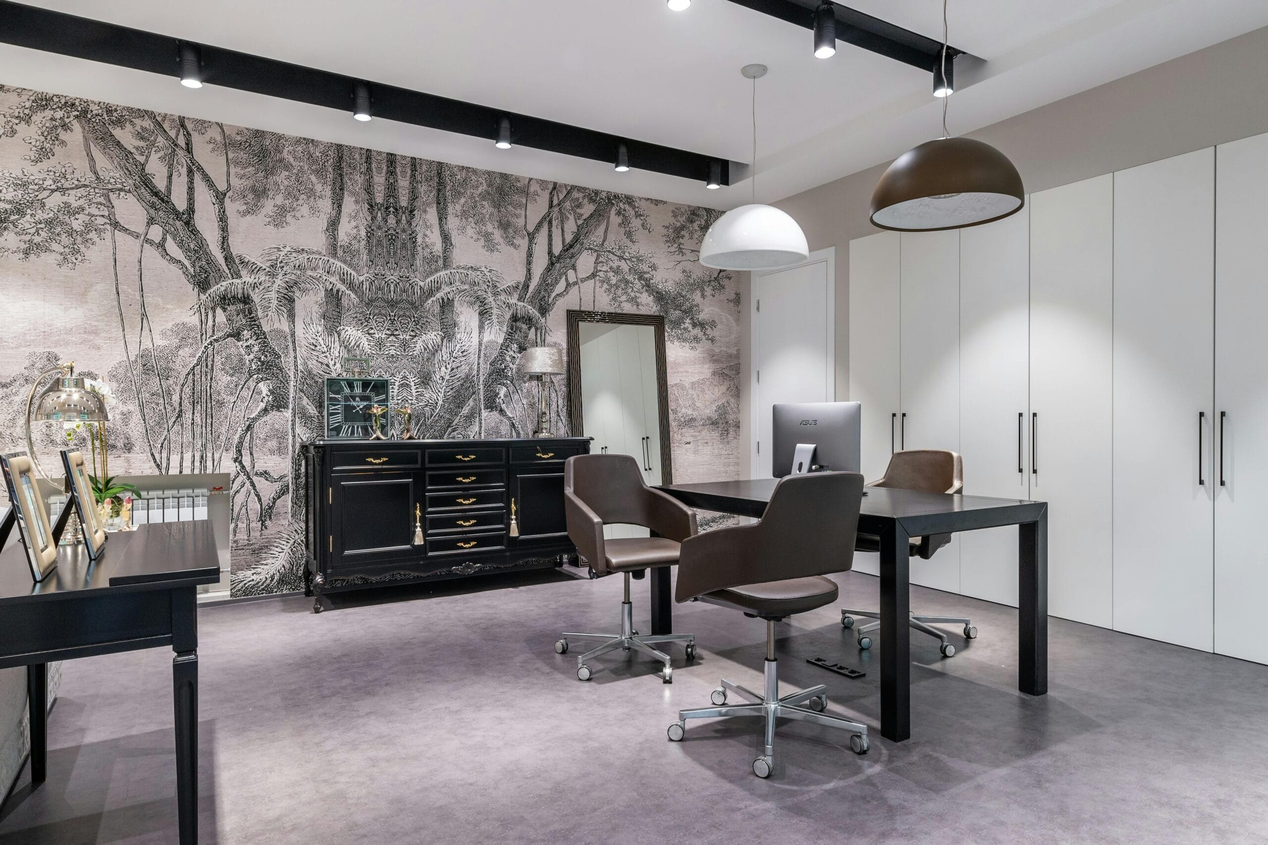 Modern computer on table placed in spacious light room with cabinet near mirror in stylish apartment with closet and decorative elements